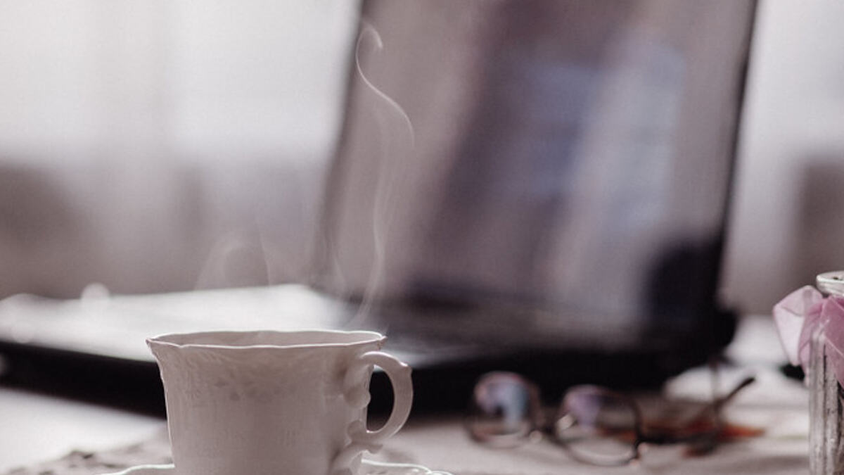 A coffee cup and an open laptop on a table