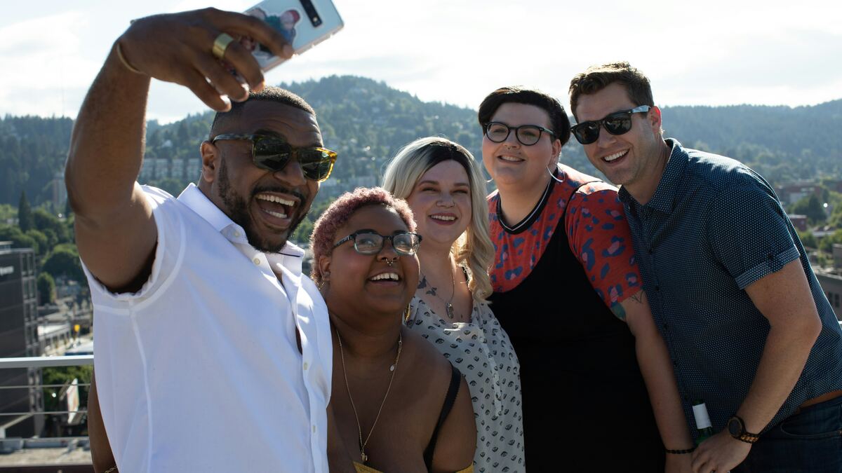 A group of coworkers crowding in for a rooftop selfie